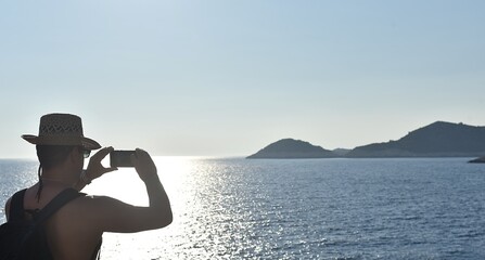 a man takes photos of the sunset on the island of Mljet with his mobile phone