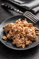 Canned tuna fish on the plate on black table.