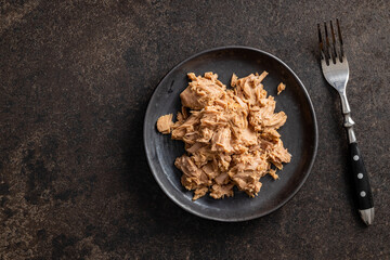 Canned tuna fish on the plate on black table.