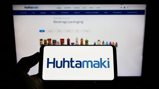 Stuttgart, Germany - 09-08-2022: Person holding cellphone with logo of Finnish packaging company Huhtamaki Oyj on screen in front of business webpage. Focus on phone display.