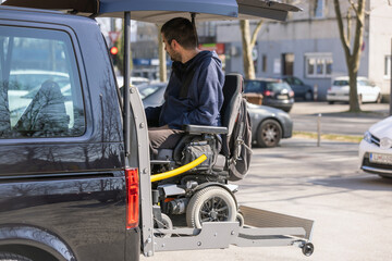 Man with disability using hydraulic wheelchair lift to get in the van, after a summer day spent on beautiful mountain nature