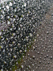 Background of many raindrops on glass. A green umbrella can be seen in the water bubbles.