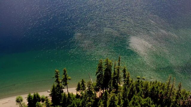 Aerial pull back of blue water lake surrounded by mountains