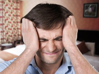 Fototapeta premium Stressed young man with headache or migraine. Tired
