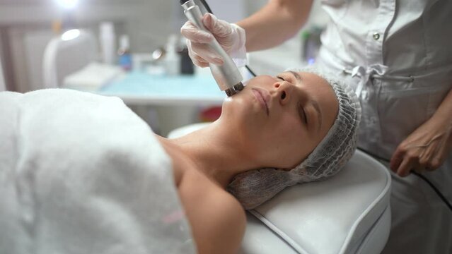 Lovely caucasian female getting RF lifting procedure of face and neck area at cosmetology clinic. Non surgery cosmetology, professional skincare, beauty treatment concept.
