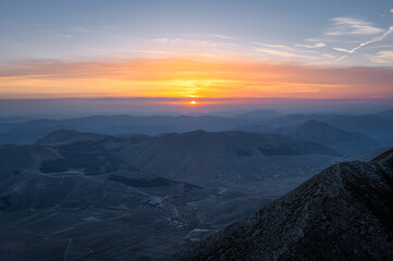 il tramonto su pian grande di castellucio visto dai monti sibillini, da cima del lago. in lontananza il riflesso del sole sul lago trasimeno