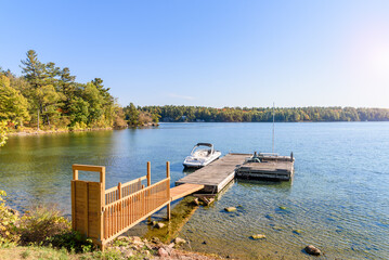 Wooden jetty and floting poontun on the bank of a might river on a sunny autumn day. A motorboat is moored to the pontoon.