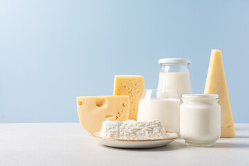 Variety of dairy products on blue background. Bottle of milk, cheese,  yogurt or sour cream, cottage cheese. Farm dairy products concept