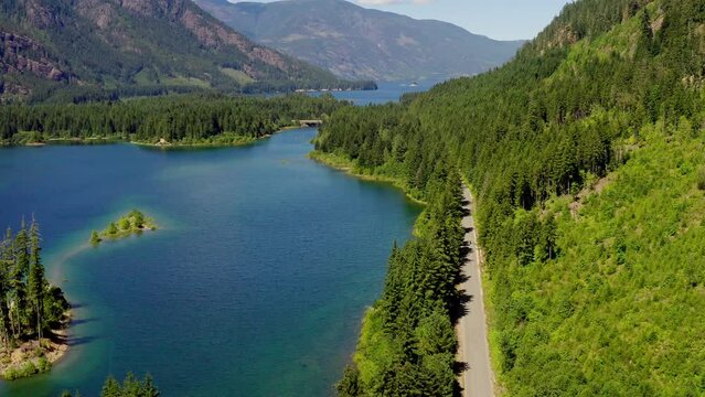 
Aerial Drone Of Motorcycle Driving On Beautiful Road Beside Mountain Lake