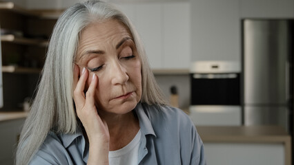 Disappointed sad elder caucasian woman grey-haired lady mature miserable woman hold hand on head...