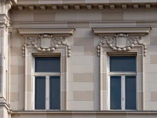 Close-up photo of two vintage-style windows on a brown facade