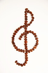 Coffee beans in the form of a treble clef on a white background. View from above.