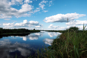 Clouds reflections in the water.  Wild river nature with Moody cloudscape. Rushes by swamp and beautiful dramatic sky. Countryside landscape in polish Biebrza National Park.