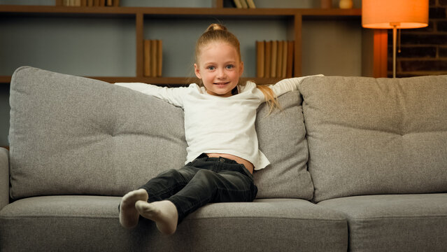 Small Blonde School Toddler Child Active Kid Falling Down On Comfortable Sofa Cozy Couch For Daytime Break Relaxation Time Little Girl Enjoying Holidays At Home Living Room Interior Carefree Weekend