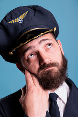 Thoughtful airline pilot in uniform looking upwards, thinking, dreaming, face closeup. Pensive dreamy plane captain with doubtful uncertain facial expression close view portrait