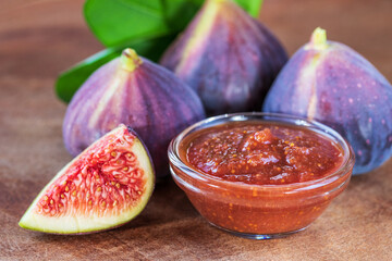 Sweet figs jam and raw figs closeup, on a wooden background. Figs whole and cut into halves. Organic gardening