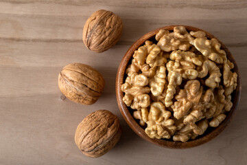 Peeled walnuts and whole walnuts in wooden bowl
