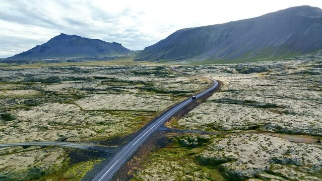 Aerial View Shot of car driving through volcanic land, Iceland, Europe.