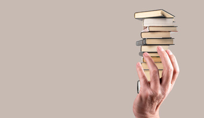 Banner with hand holding books stack on grey background. Knowledge, intellectual development,...