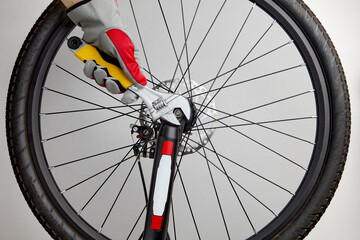 Hands in protective gloves with an adjustable wrench unscrew the bicycle wheel. Diy bicycle repair