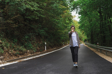 beautiful girl walks in the forest near the road