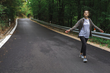 beautiful girl walks in the forest near the road