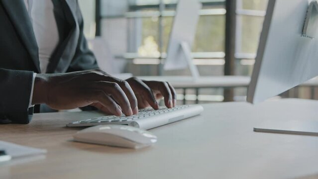 Close up african american specialist programmer businessman working computer in modern office typing on keyboard coding trading online developing web java app chatting with colleagues emailing message