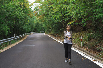 beautiful girl walks in the forest near the road