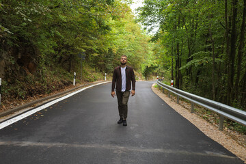 a young man is walking near the road and in the forest