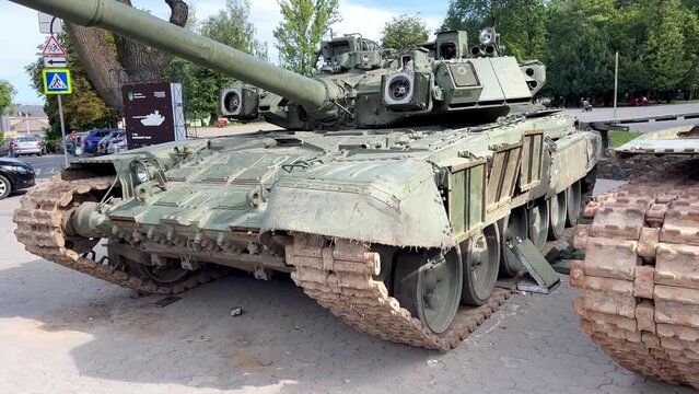 Damaged Russian T-90 tanks with broken navigation equipment stand on the streets of the city. Knocked out Russian tanks in the war in Ukraine. Exhibition of defused tanks in cities of Ukraine.
