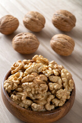 Peeled walnuts and whole walnuts in wooden bowl