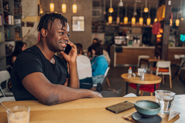 African american man using smartphone while drinking coffee in a cafe