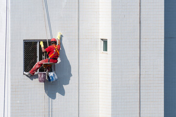 Trabalhadores da construção civil fazendo manutenção predial por meio de rapel