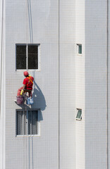 Naklejka premium Trabalhadores da construção civil fazendo manutenção predial por meio de rapel