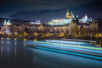 Fototapeta premium Hradcany, St Vitus Cathedral and Vltava river at night with blurred boat, Prague