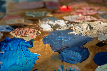 Oil paint mixed on an artist's improvised cardboard paint pallet. Blues, whites, yellows and reds are mixed on a palette in preparation for a painting