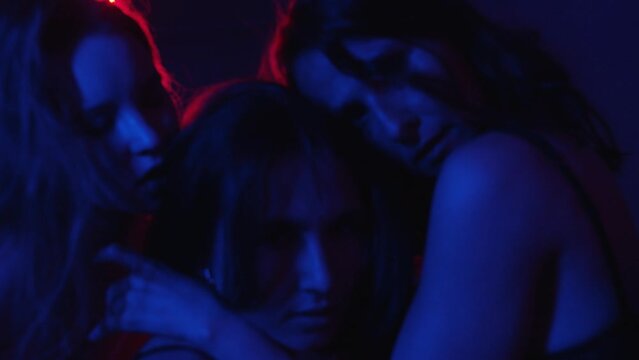 Three sexy women giving erotic show in the private room in neon lighting