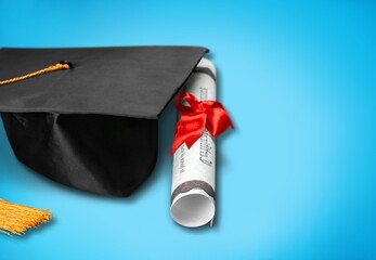 High school graduation hat and diploma on blue background. School education and graduation concept.