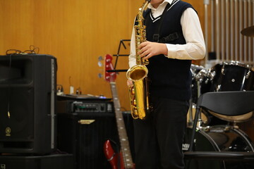 Fototapeta premium A guy playing a saxophone standing blows into a golden brass musical instrument.One musician in the studio closeup