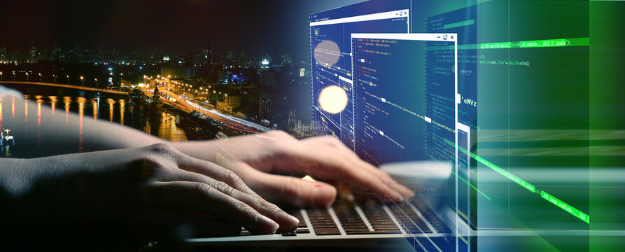 Double exposure of programmer with laptop in office and night city