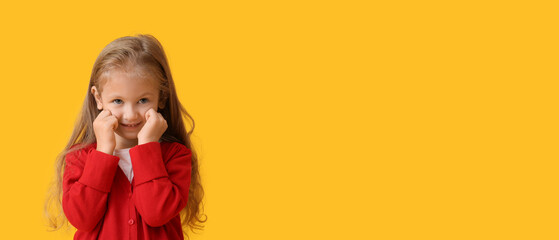 Cute little girl in warm sweater on yellow background with space for text
