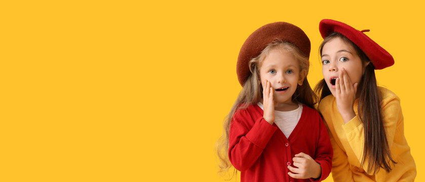Surprised little girls in warm sweaters on yellow background with space for text