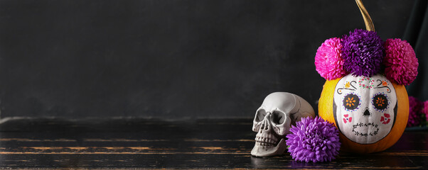 Pumpkin with painted skull on dark background. Celebration of Mexico's Day of the Dead or Halloween