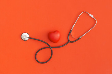 Stethoscope and heart on red background. Top view. Flat lay. Medicine concept.