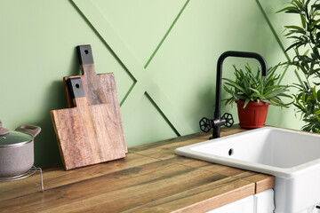 Counters with cutting boards and sink near green wall