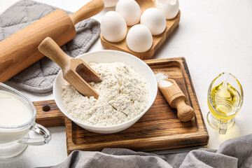 Wooden board with bowl of flour and sugar on table