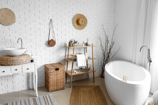 Interior of cozy bathroom with sink, shelving unit and laundry basket