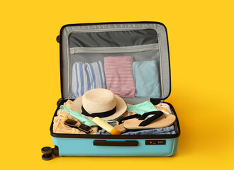 Fototapeta premium Open suitcase with beach accessories and clothes on color background