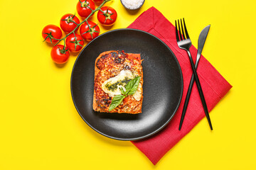 Plate of tasty Italian pie and tomatoes on yellow background