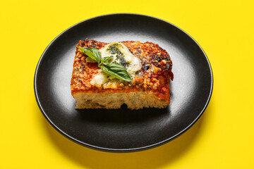 Plate with piece of tasty Italian pie on yellow background